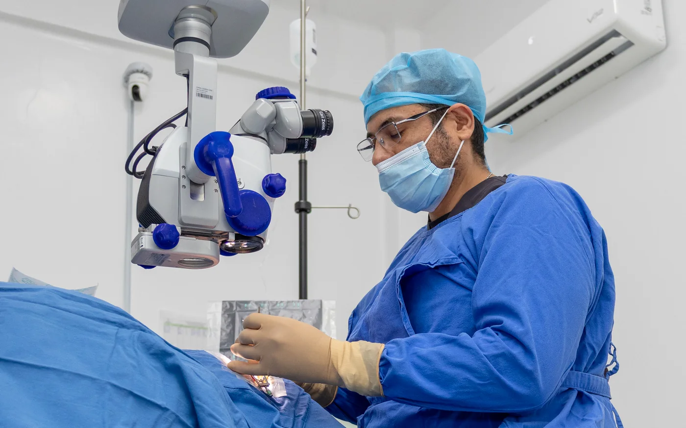 Cirujano oftalmólogo operando con microscopio Zeiss durante una cirugía de glaucoma