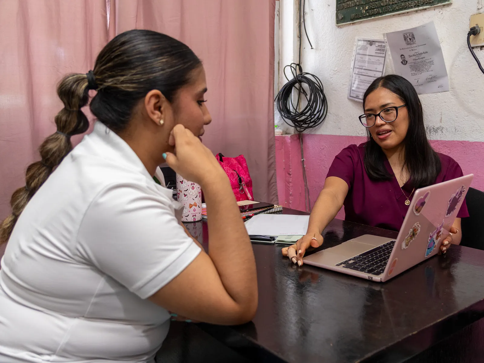 Integrante del equipo conversa con una joven frente a una laptop durante la atención