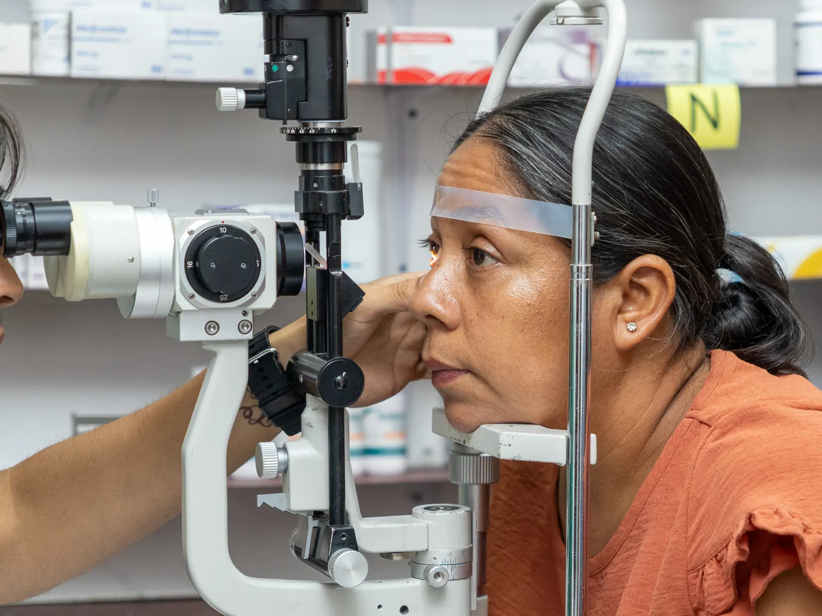 Paciente apoya la frente en una lámpara de hendidura durante la revisión de sus ojos