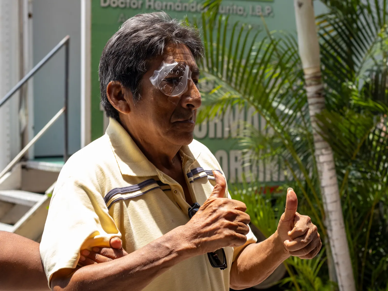 Paciente con protector en el ojo levanta ambos pulgares frente a la unidad móvil